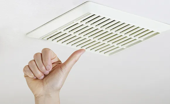 Person removing or replacing residential air vent cover for air duct disinfecting service in Appleton.