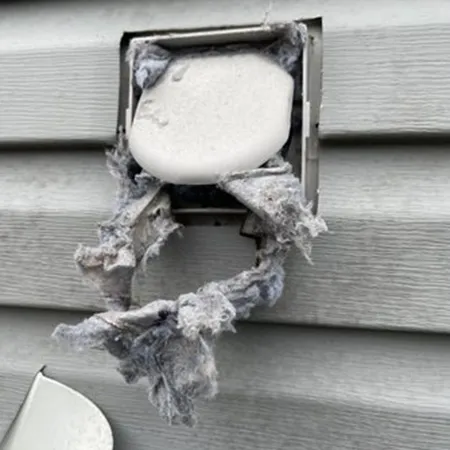 Exterior dryer vent clogged with heavy lint buildup highlighting need for professional air duct cleaning services.