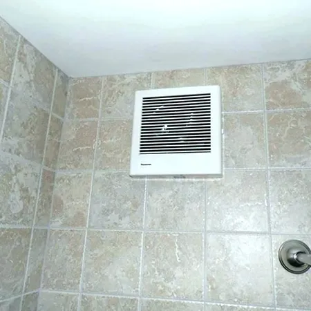 Cleaned bathroom floor vent embedded in beige tile floor showing benefits of professional bathroom fan cleaning services.