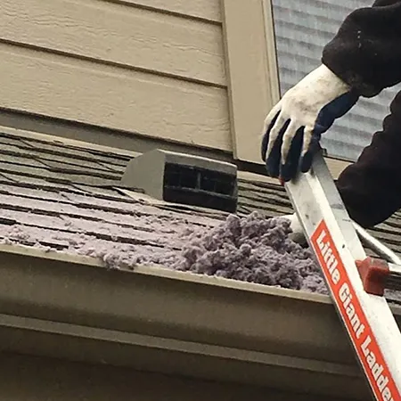 Professional technician clearing dense bird nest debris from blocked dryer vent outside Marinette WI home
