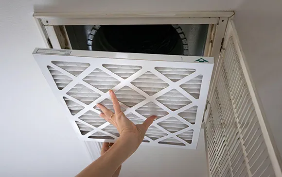 Hand inserting a new HEPA air filter into an air vent for maximum air purification.