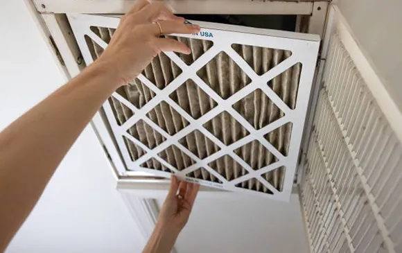 Person installing or removing white air filter from HVAC system for improved air quality