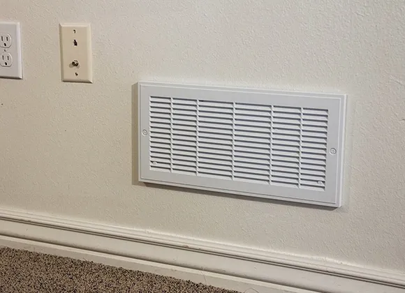 Clean wall air vent installed near electrical outlets in a commercial space.