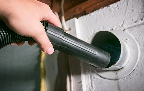 Comprehensive dryer vent maintenance services showing hand inspecting dryer vent pipe connection.
