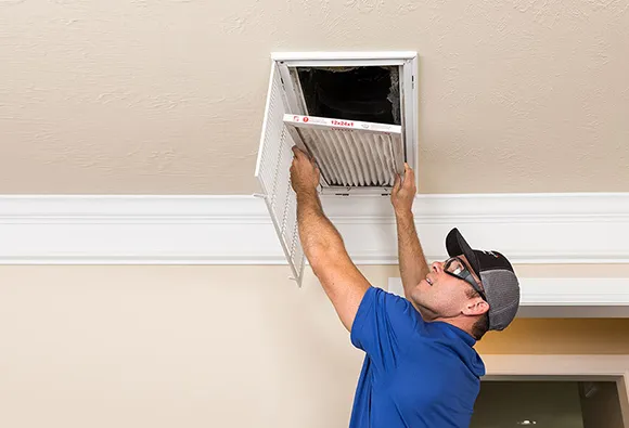 Comprehensive HVAC duct cleaning service with technician removing ceiling air vent grille in West Bend WI.