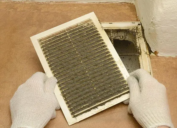 Close-up of hands holding dirty air filter with dust and mold for comprehensive air duct mold inspection in Manitowoc WI.
