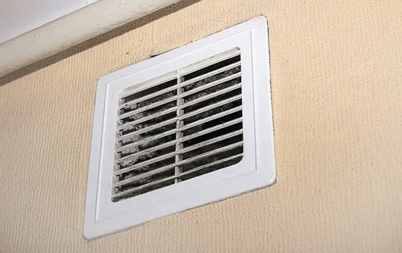 Effective air duct mold removal service showing wall-mounted air vent grille in Oshkosh WI.