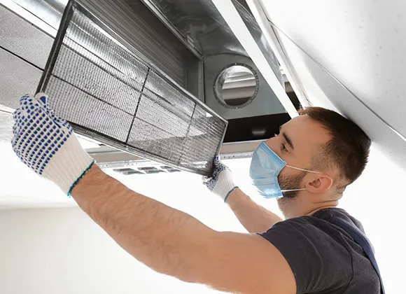Technician servicing commercial air duct with metal ducts during air duct sanitization in West Bend WI.