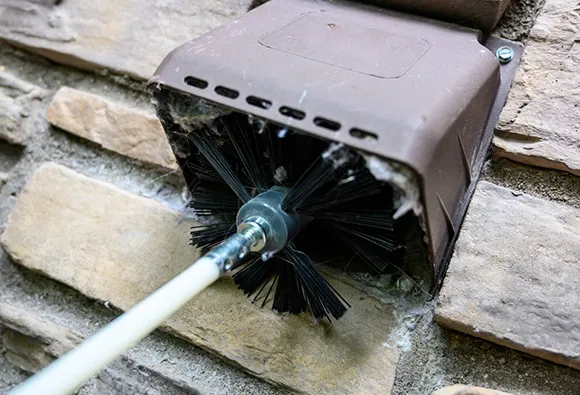 Rotating brush cleaning lint and debris inside a clogged dryer vent tube.