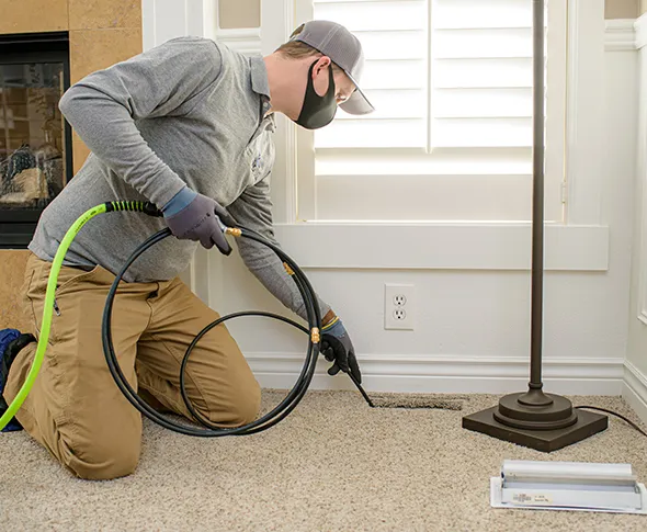 Professional technician sanitizing air ducts with spray equipment in Brookfield WI home.