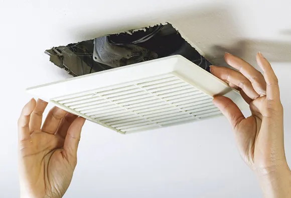 Expert bathroom fan cleaning service removing exhaust fan cover to improve ventilation in Manitowoc WI.