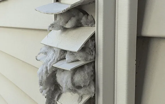 Clogged dryer vent pipe filled with lint and debris causing airflow obstruction.
