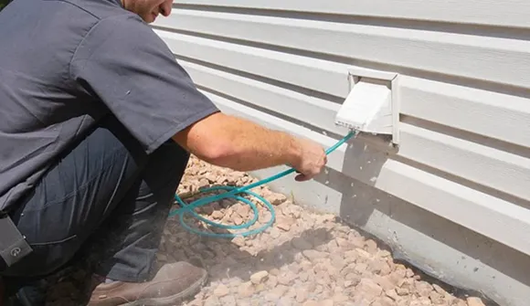 Expert dryer vent cleaning service technician removing lint and debris from exterior dryer vent in Oshkosh WI.