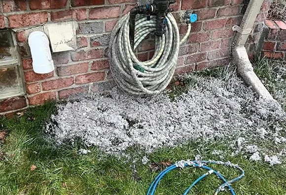 Clogged outdoor dryer vent with debris buildup near brick wall for fast and effective dryer vent cleaning in Appleton.