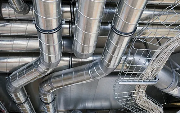 Close-up of shiny industrial metal air ducts and ventilation system pipes.