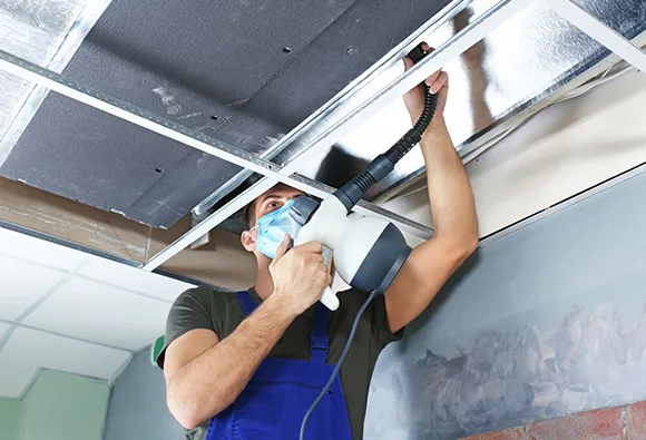 Professional performing commercial dryer vent cleaning wearing protective mask in Manitowoc WI.