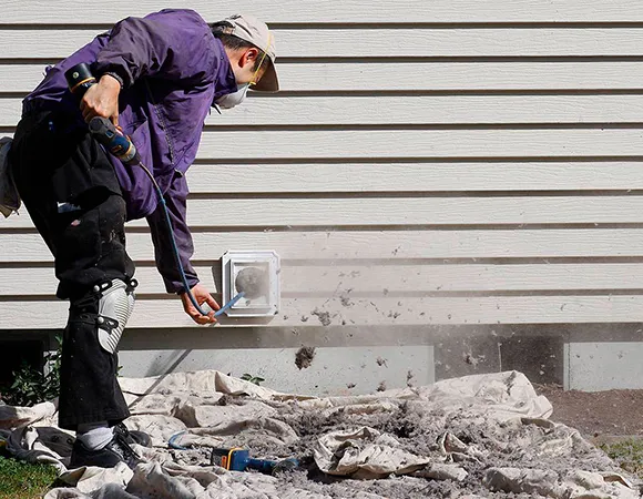 Technician clearing large clumps of lint and debris from exterior of dryer vent in Oshkosh WI.