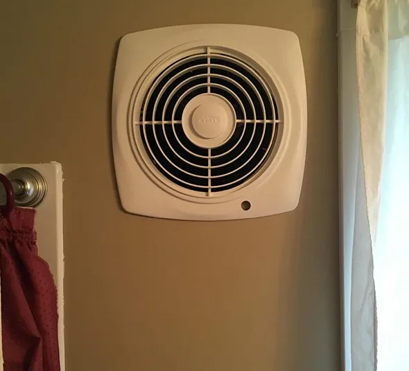 Bathroom ventilation fan installed on wall with fan grille in Oshkosh WI home needing professional cleaning.