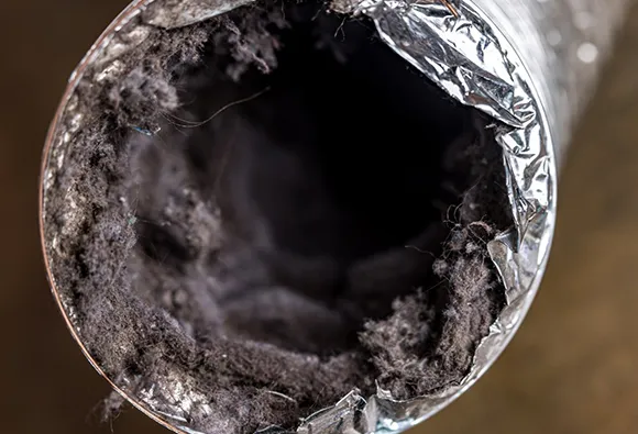 Close-up view showing heavy lint buildup and dirt inside dryer vent during cleaning in Milwaukee WI.