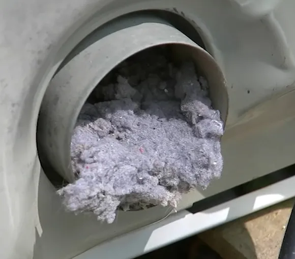 Close-up of dryer vent clogged with thick white lint buildup inside the duct.