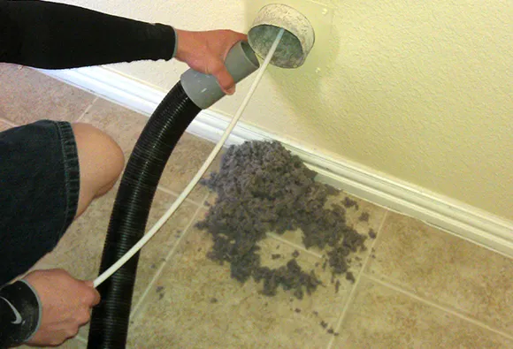Professional vacuuming and maintenance of dryer vent system in basement during routine safety inspection in Green Bay WI.