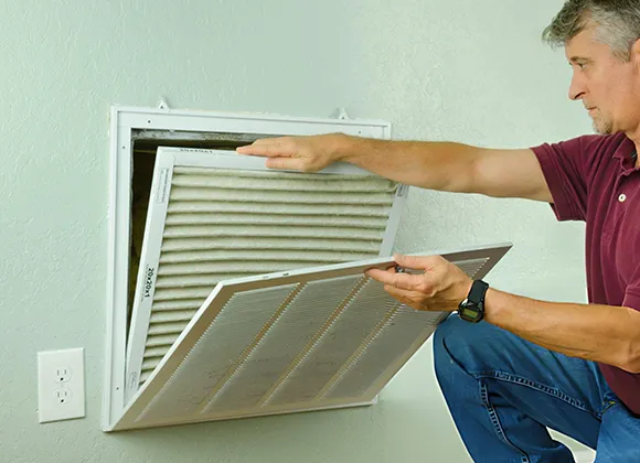 Trusted air duct cleaning company technician removing indoor vent grille for cleaning service.