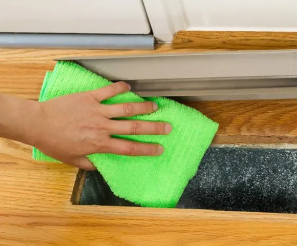 Professional air duct cleaning service using vacuum hose to remove dust from ceiling air vents in Marinette WI.