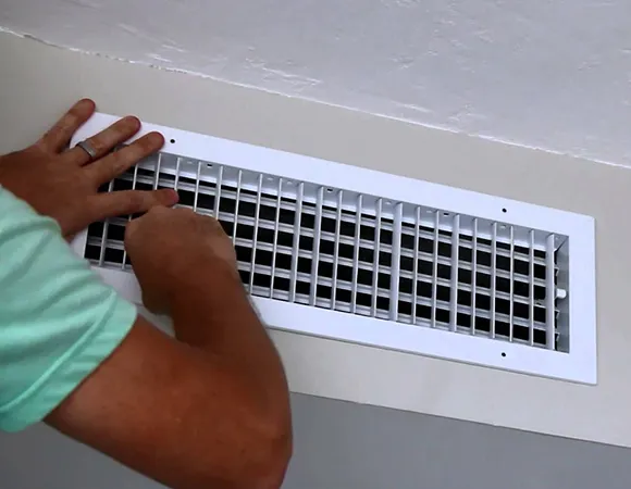 Technician cleaning clogged exterior dryer vent filled with lint and debris in West Bend WI.