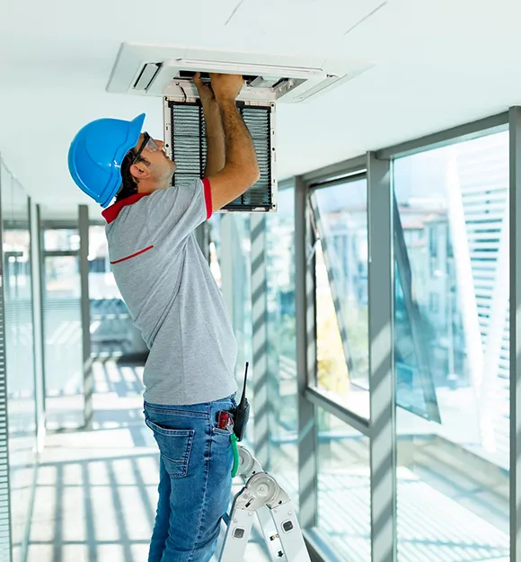 Professional commercial HVAC technician cleaning air duct vents in modern Madison office